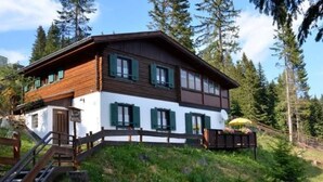 A two-story wooden chalet with green shutters, a wooden deck, and a satellite dish. - Almhaus am Hohenwart by Interhome (Klippitztörl)