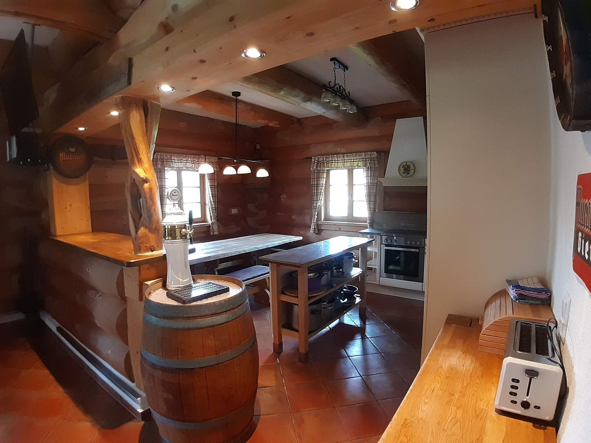 Une cuisine rustique avec des poutres en bois, un îlot central, une cuisinière et un grille-pain.