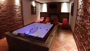 A spa room with a hot tub, red lounge chairs, and a fireplace. - Schönberghütte by Interhome (Niederwölz)