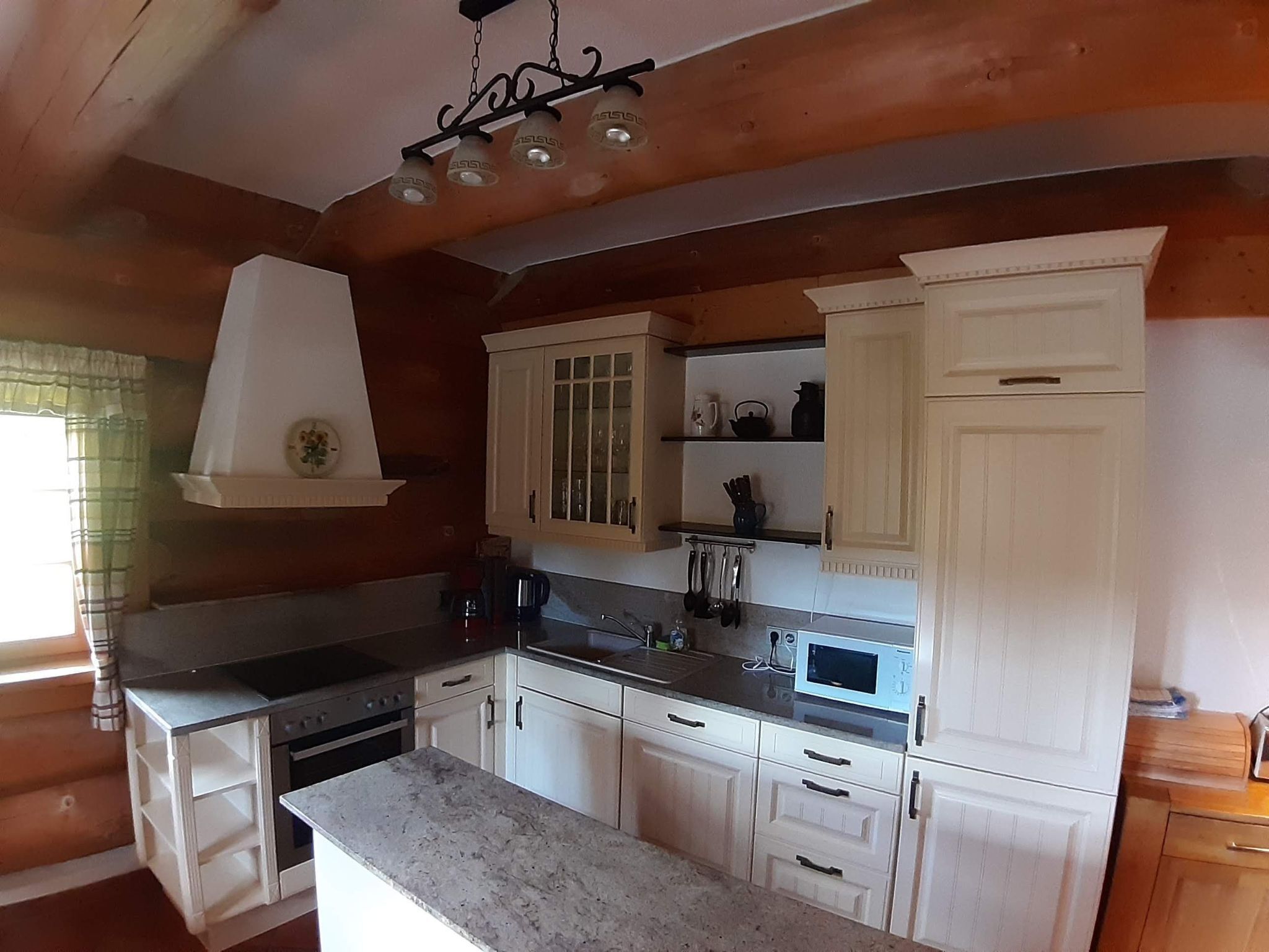A kitchen with white cabinets, a granite countertop, a stove, and a microwave.