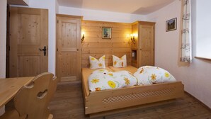 Ein hölzernes Bett mit Blumenbettwäsche in einem Zimmer mit Holzwänden und -türen.