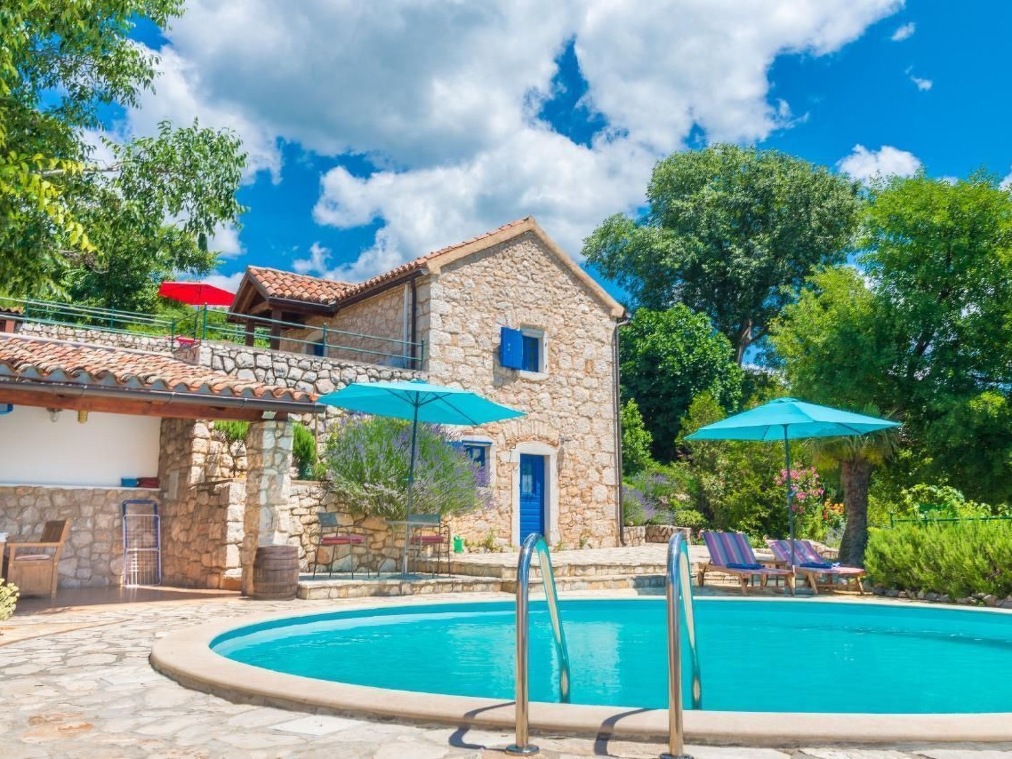 A stone building with a pool, outdoor seating, and umbrellas.