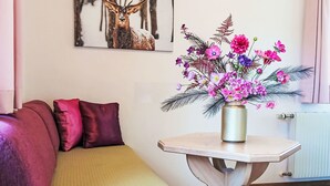 A room with a sofa, a small table with a vase of flowers, and a wall-mounted picture. - Gsenger Natur in Abtenau by Interhome (Abtenau)