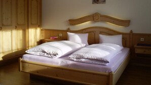 A wooden bed with white linens in a room with wooden wardrobes and a painting on the wall. - Gsenger Natur in Abtenau by Interhome (Abtenau)