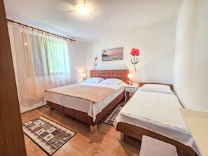 Ein Hotelzimmer mit zwei Betten, Holzboden, Teppich, einem Gemälde und einem Fenster mit Vorhängen.