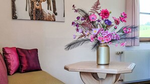 A room with a bed, a small table with a vase of flowers, and a window with curtains. - Gsenger in Abtenau by Interhome (Abtenau)