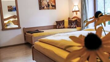 A hotel room with a bed, a mirror, a painting, a lamp, and a window.