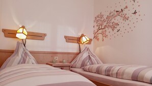 Een hotelkamer met twee bedden, elk voorzien van gestreept beddengoed en hoofdeinden met wandlampen.