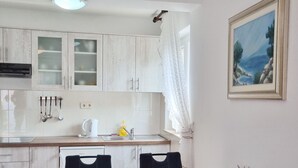 A kitchen with white cabinets, a sink, and a dining table with chairs. - Barbalić by Interhome (Krk/Baška)
