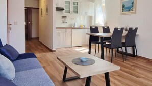A modern living room with a sofa, a dining table with chairs, and a kitchen in the background. - Barbalić by Interhome (Krk/Baška)