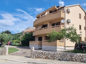A multi-story building with balconies, a stone wall in front, and a mountain in the background. - Barbalić by Interhome (Krk/Baška)