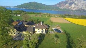 Una casa con paneles solares, piscina y vistas a un lago y montañas.