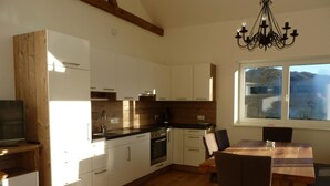 Una cocina moderna con armarios blancos, encimera de madera y un comedor con mesa y sillas.
