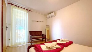 Una camera d'albergo con un letto, una panca, uno specchio e un condizionatore.