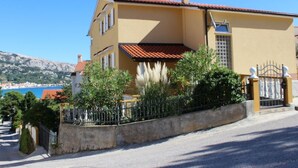 Un edificio a due piani con tetto in tegole rosse, un balcone e un cancello.