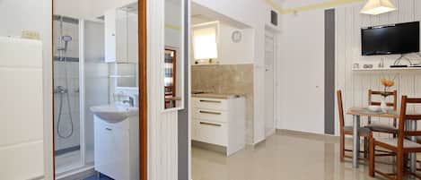 A modern kitchen with white cabinets, a built-in oven, and a dining area with a table and chairs.