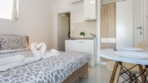 Une chambre d’hôtel moderne équipée d’un lit, d’une kitchenette, d’une salle de bain et offrant une vue sur l’extérieur.
