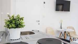 Une cuisine moderne dotée d’une cuisinière intégrée, d’un évier blanc et d’une plante en pot posée sur le plan de travail.