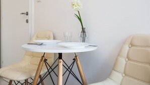 Une petite table ronde avec deux chaises, un vase contenant une seule fleur blanche et deux verres.
