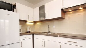 A modern kitchen with white cabinets, a stainless steel sink, and a built-in microwave. - Wohnung in Baška mit Eigenem Balkon by Interhome (Krk/Baška)