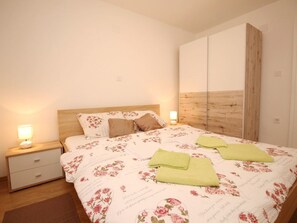Un dormitorio con estructura de cama de madera, una mesita de noche con lámpara y un armario con espejo.