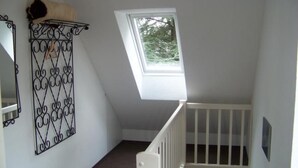 A room with a sloped ceiling, a small window, a white crib, and a decorative metal wall piece. - Haus am Reithmoor by Interhome (Großefehn)