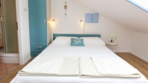 A neatly made bed with a pillow, a small bedside table with a plant, and a wall-mounted light fixture. - C. Silvija Bs by Interhome (Krk/Baška)