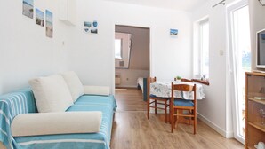A cozy living room with a sofa, a dining table with chairs, and a TV on a wooden shelf. - C. Silvija Bs by Interhome (Krk/Baška)
