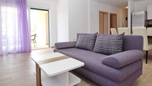 A modern living room with a purple sofa, a white coffee table, and a dining area in the background. - Appartement in Baška mit Terrasse by Interhome (Krk/Baška)
