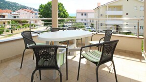A balcony with a round table and four chairs, overlooking a residential area with houses and a mountain in the background. - Appartement in Baška mit Terrasse by Interhome (Krk/Baška)