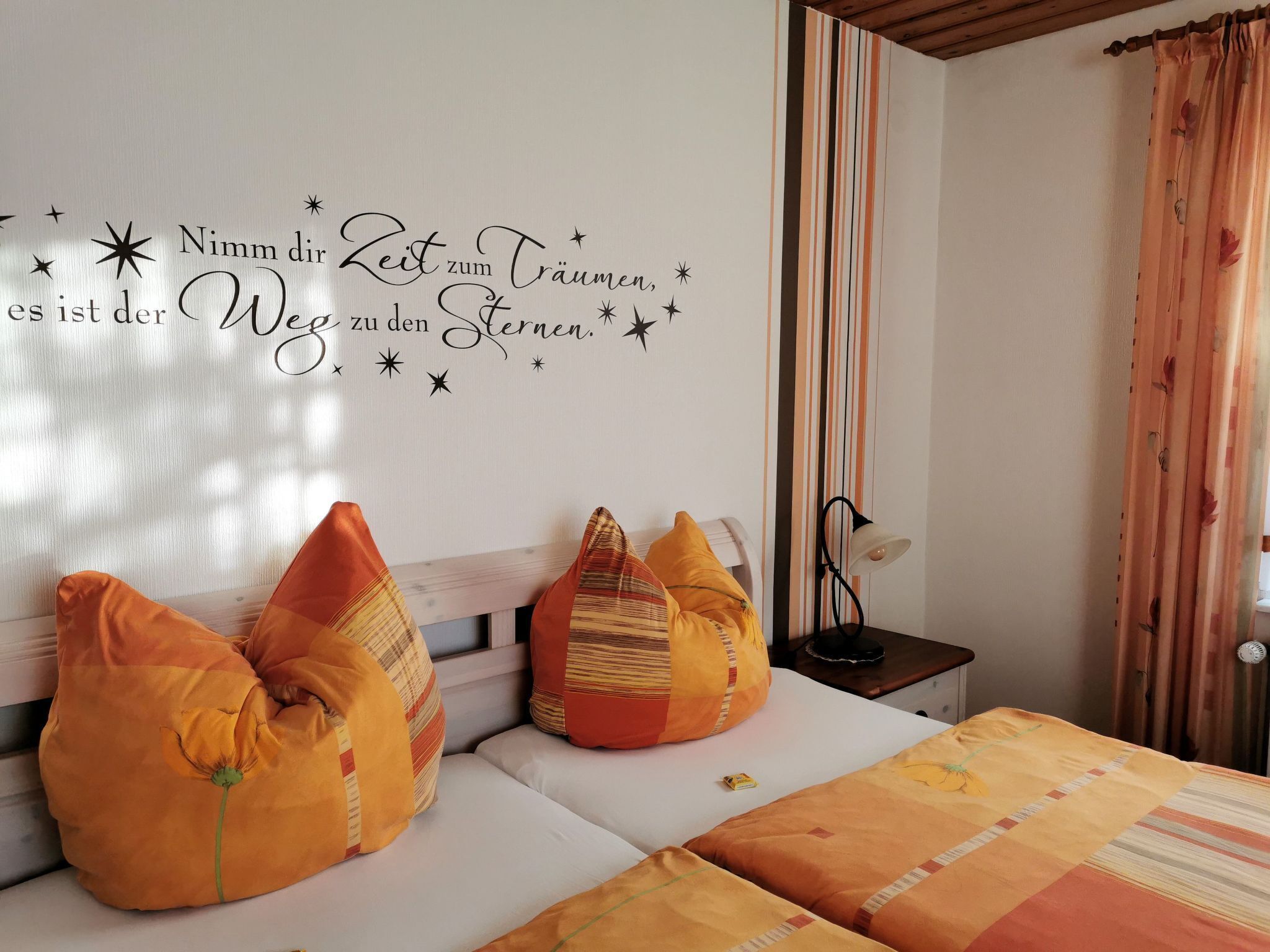 Une chambre à coucher avec un lit, des oreillers, une table de chevet, une lampe et un élément décoratif mural.