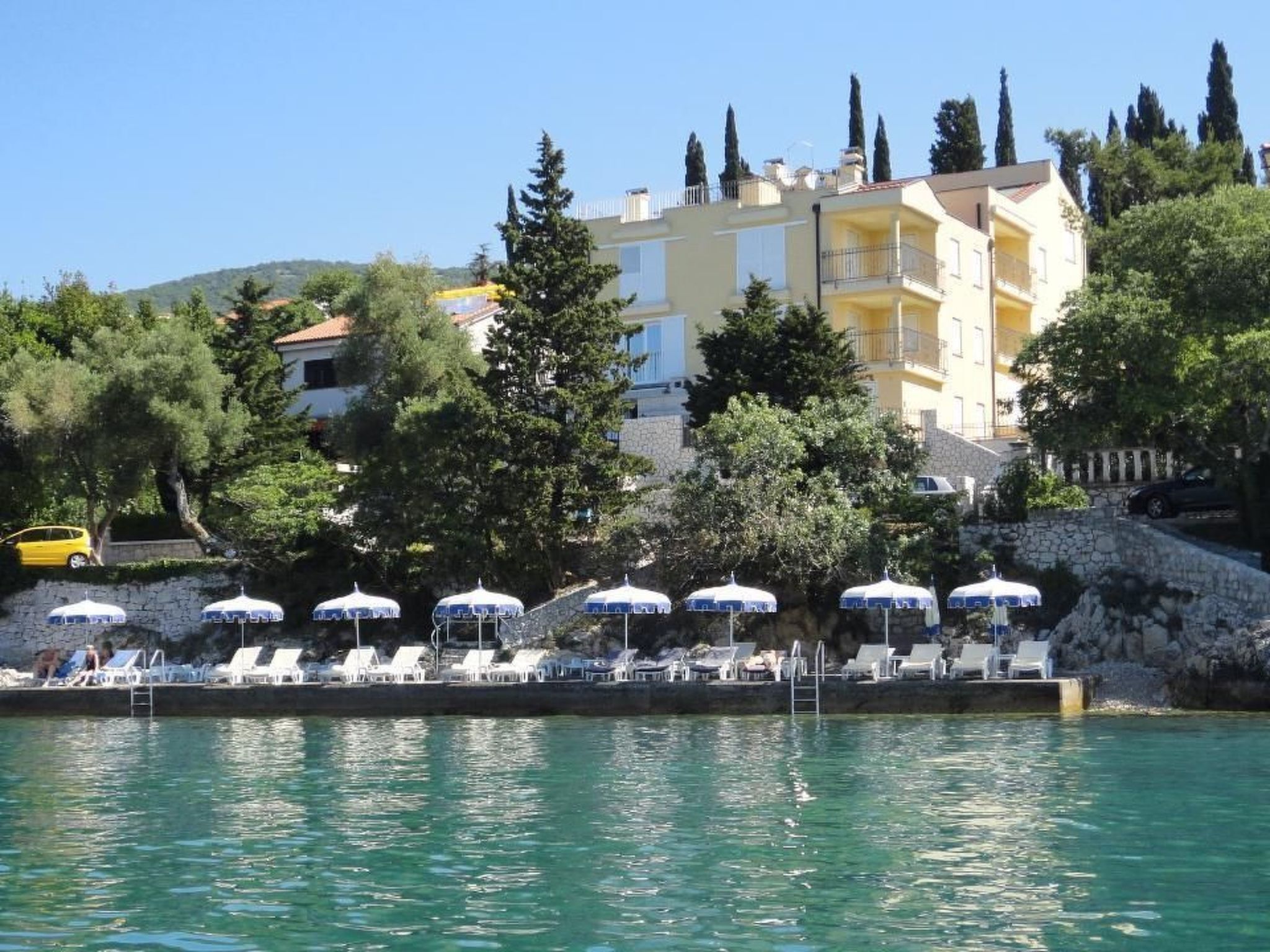 Ein Küstenhotel mit Poolbereich, Liegestühlen und Sonnenschirmen.
