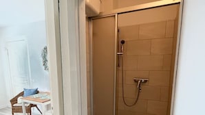 A bathroom with a shower, toilet, and a small table with a chair. - Haus Nordstern by Interhome (Kalifornien)