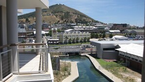 Vista desde un balcón sobre un río, con edificios y una colina al fondo.