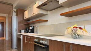 Una cocina moderna con armarios de madera, horno de acero inoxidable, cafetera y frutero en la encimera.