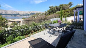 A patio with a table and chairs overlooking a lake and mountains. - Lavanda4 by Interhome (Krk/Baška)