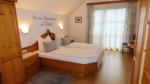 Ein Schlafzimmer mit einem Holzbett, einem Nachttisch, einer Kommode und einer Wandleuchte.
