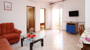 A living room with a sofa, a glass coffee table, and a TV mounted on the wall. - Appartement in Baška mit Eigenem Balkon by Interhome (Krk/Baška)