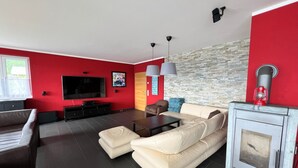 Un soggiorno moderno con una parete di accentuazione rossa, una TV a schermo piatto, un camino e una parete decorativa in pietra.
