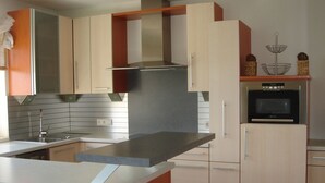 Une cuisine moderne dotée d’un îlot central, d’appareils électroménagers en acier inoxydable et de meubles de couleur claire.