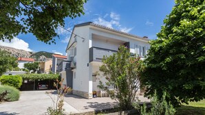 A modern two-story house with a balcony, surrounded by greenery and a clear sky. - Appartement in Baška mit Eigenem Balkon by Interhome (Krk/Baška)