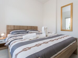 A neatly made bed with a striped bedspread, a wooden headboard, and a large mirror on the wall. - Nettes Appartement in Baška mit Eigenem Balkon by Interhome (Krk/Baška)