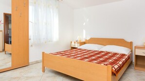 Een slaapkamer met een houten bed, een nachtkastje, een spiegel en een kledingkast.