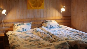 Um quarto de madeira com uma cama, duas luminárias de cabeceira e um ornamento amarelo na parede.
