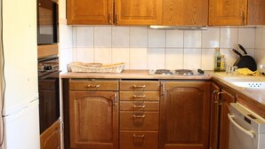 Cozinha com armários de madeira, bancada, fogão e lava-louças.