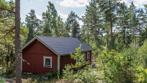 A small red cabin surrounded by dense forest. - "Skogsmullehaus" mit Terrasse by Interhome (Loftahammar)