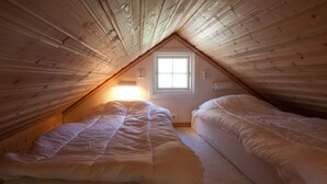 A small attic bedroom with two single beds, a sloped ceiling, and a window providing natural light. - Holzhaus mit überdachter Terrasse by Interhome (Bräkne-Hoby)