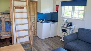A compact kitchen with a built-in oven, a sink, and a stove. There is a wooden ladder leading to a lofted sleeping area. - Holzhaus mit überdachter Terrasse by Interhome (Bräkne-Hoby)