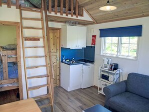 A compact kitchen with a built-in oven, a sink, and a stove. There is a wooden ladder leading to a lofted sleeping area. - Holzhaus mit überdachter Terrasse by Interhome (Bräkne-Hoby)