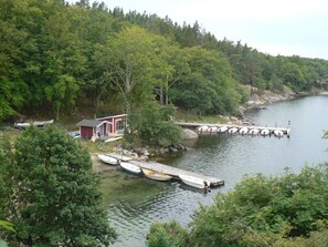Una cabaña junto al lago con barcos amarrados, rodeada de un bosque frondoso.